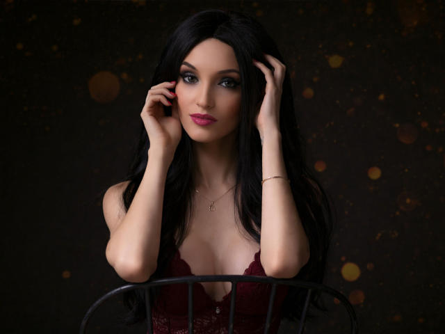 Digitale kunst van MaiaMoxie, een aantrekkelijke vrouw met lang zwart haar, bleke huid en rode lippenstift, die voorover leunt met haar handen. in het haar, met een diep uitgesneden donkerrode top, donkere achtergrond. Bokeh-verlichting.