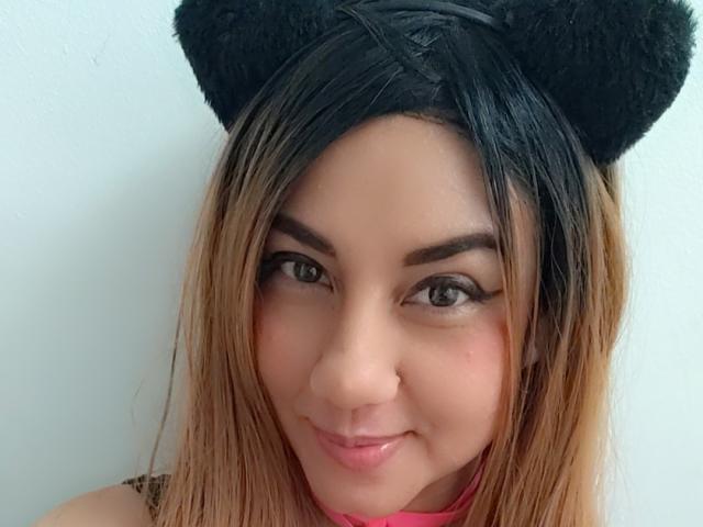 LunaWii has light brown skin, black cat ears, and blonde hair, with a small nose and a cute smile, wearing a pink choker. Her eyes are brown and she's looking at the camera.