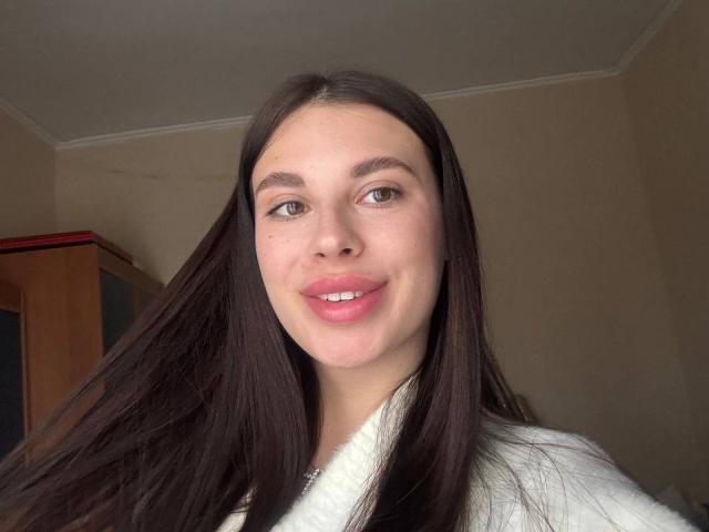 Photo en gros plan de BlackFatal, une jeune femme aux longs cheveux noirs, à la peau claire et aux yeux marron, souriant légèrement avec du rouge à lèvres rose. lèvres.

elle porte une chemise blanche, ce qui crée un contraste saisissant. Tellement mignonne..