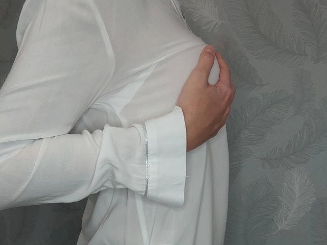 Svenjah1-hot's hand is gripping their white shirt over their chest, showing a flat, smooth, and slightly taut torso. Svenjah1-hot's shirt is long-sleeved and white.
