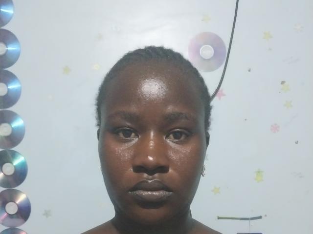 CathrynStella's face is centered with dark brown skin, small earrings, and her shiny, slicked-back hair. She's looking straight at the camera with a neutral expression.