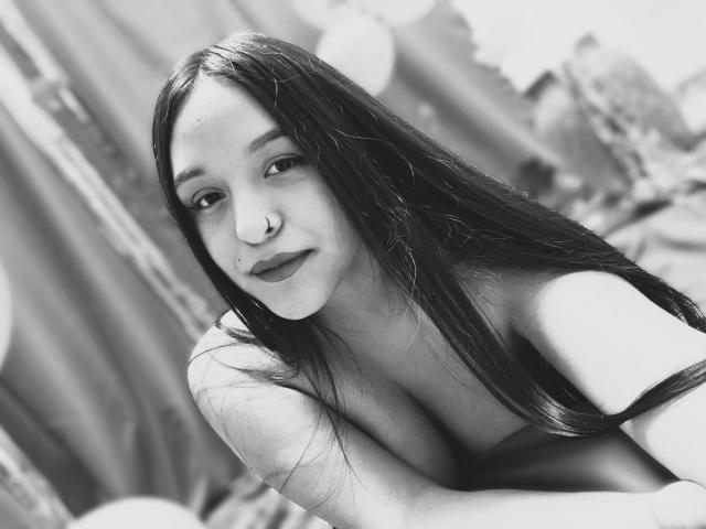 MarianaVargasX has long dark hair, a nose ring, and is topless with small tits, smiling at the camera in a black-and-white photo.