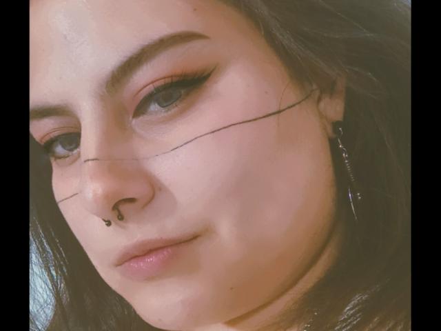 LilithHeavy heeft een neusring, zwarte eyeliner en een dunne zwarte streep over haar wang. Ze heeft bruine ogen, donkere wenkbrauwen en draagt een zilveren oorbel..