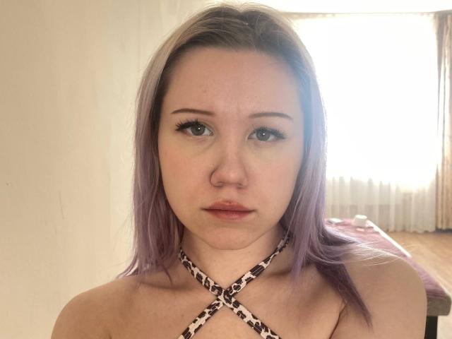 MirnaTeaster has light purple hair, a nose ring, and a leopard print halter top, showing her bare shoulders and a neutral expression. Her tits are small, and she's looking at the camera.