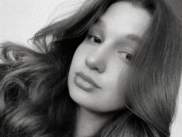 Black-and-white photo of MissKuromi with long, wavy hair, slightly parted lips, and a relaxed, half-smile expression. Her eyes are partially closed, giving a dreamy look.