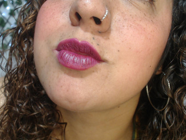 DannyEvans' face, showing a nose ring, pinkish-purple lipstick, curly brown hair, and light brown skin with small acne spots. Boobless, no visible tits or pussy.