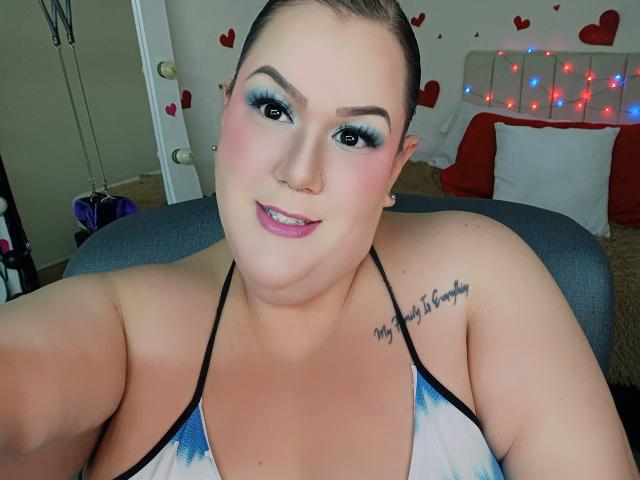 GiiannaMorrys has blue eyeshadow, pink lipstick, a nose ring, and a tattoo on her right shoulder saying "My heart is for you". She's topless with visible tits.
