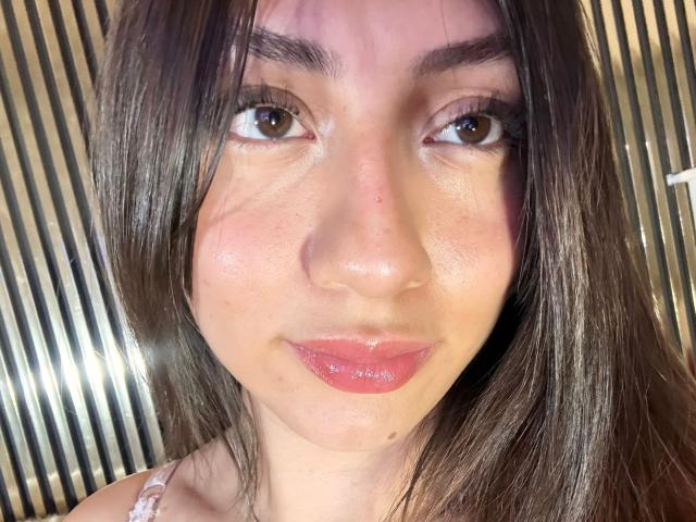 Luluberrie has shiny brown eyes, straight dark brown hair, and glossy pink lips. Her fair skin shows subtle freckles and a small mole under her right eye.