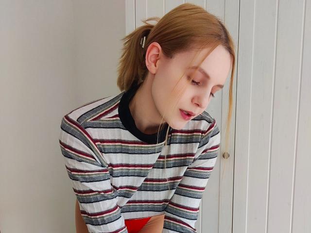 LaurenSommer-hot with red hair, striped shirt, and black collar, leaning forward, eyes down, hairclip in ponytail, soft light, subtle smile, pale skin, red underwear visible.