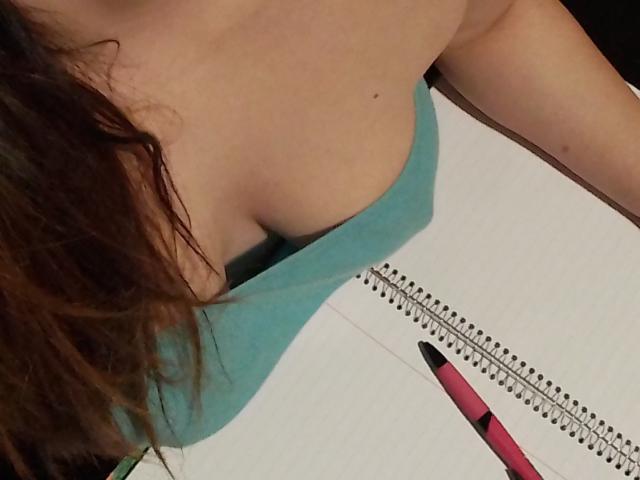 ImFireMoon's cleavage, blue tank top, wavy brown hair, white notebook, spiral binding, pink pen, partial arm, close-up.