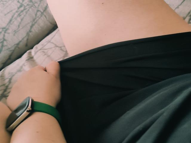 MinistraX's hand pulls up black underwear, exposing a pale, smooth upper thigh. She wears a green smartwatch on her wrist.