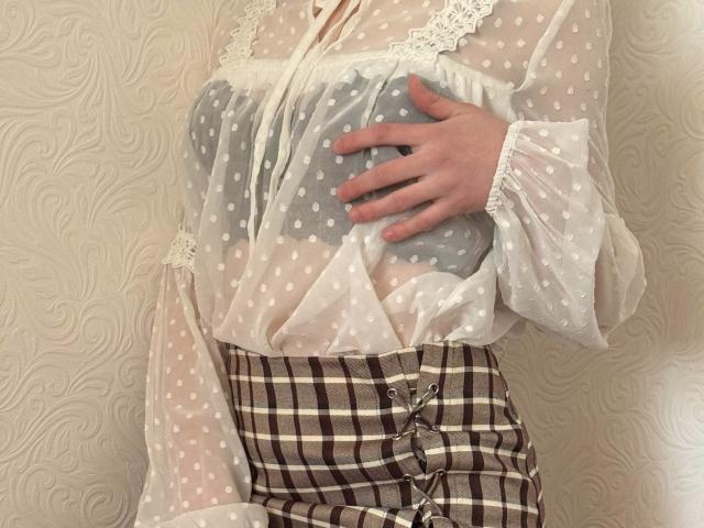 MiyaLia's sheer polka-dot top reveals her gray, perky tits, with a hand gently cupping them. She wears a plaid skirt and lace sleeves, looking sexy.
