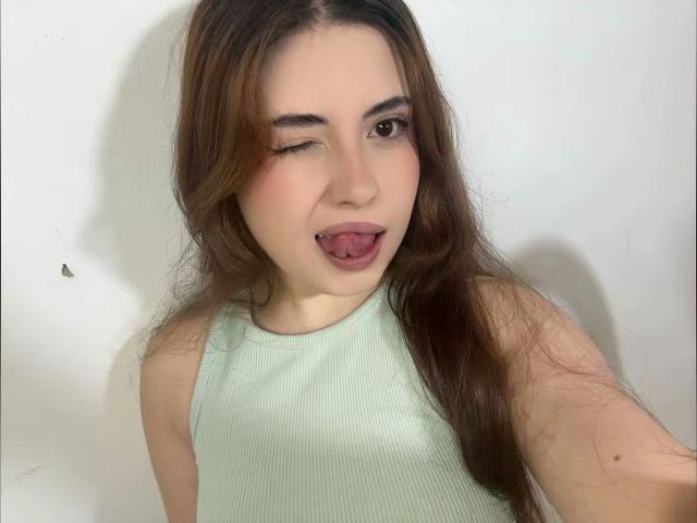 VicluX has long brown hair, winks with one eye, sticks out her tongue, and wears a green ribbed tank top, showing a cute and playful expression.