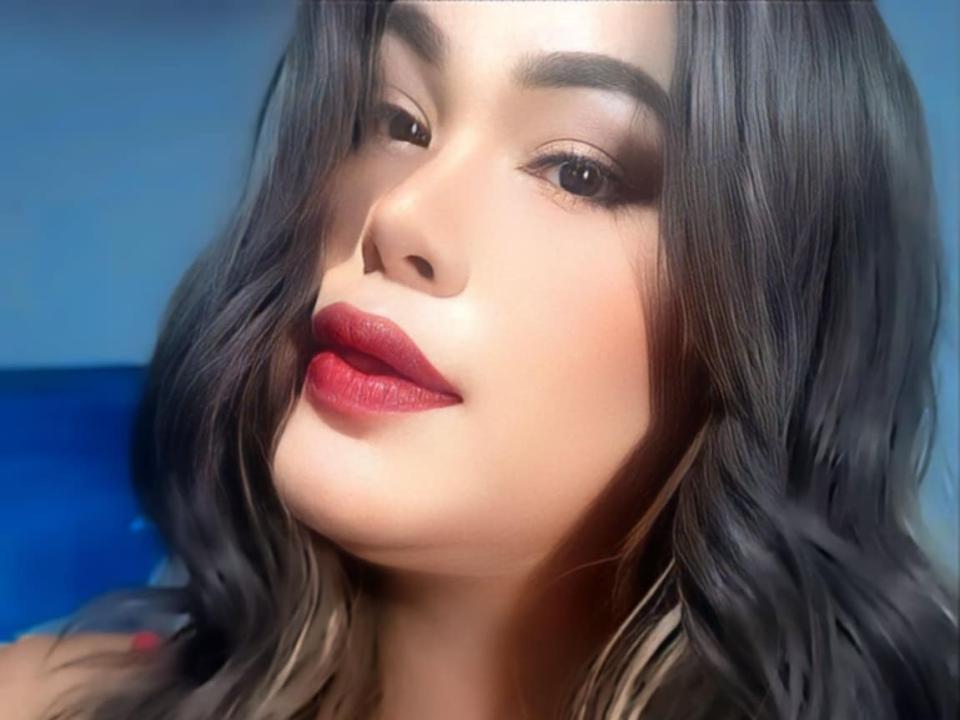 DhennisePretty has dark wavy hair, red lipstick, and a slightly parted mouth with a sexy, confident look, dark eyebrows, and subtle makeup.