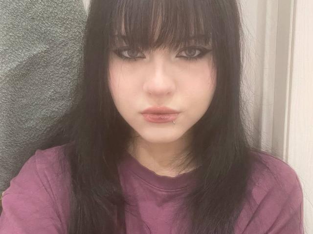 NerySenavanh ha i capelli neri, con la frangia, e un piercing al naso con un piccolo punto. Indossa una maglietta viola e le sue labbra sono leggermente socchiuse, con un piccolo piercing al labbro..