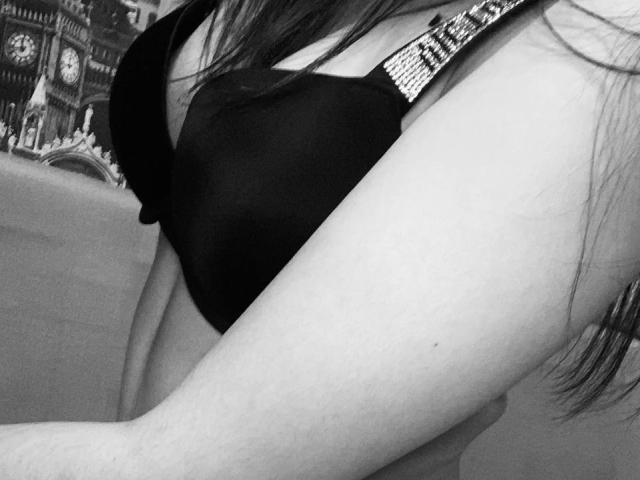 JinnyWalthers' tits in a black bra, showing her upper chest and arm. Her bra has sparkly straps. The image is a black-and-white photo.