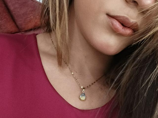 AliceCoolenk's face, focusing on her pouty pink lips, light brown hair, and a gold necklace with a teardrop pendant against a red top.