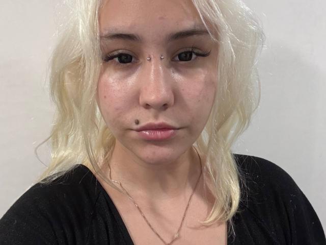Talitha Gillick ha la pelle chiara, i capelli biondi e ondulati, l'eyeliner nero, un piercing al naso, una piccola lentiggine sulla guancia destra e indossa una maglietta nera con una collana d'argento..