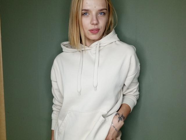 A close-up of a carved wooden coat of arms. The coat features bold, simplified shapes with a central red emblem and white border. The wood is light brown.
