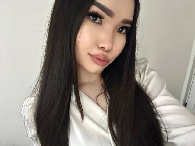 RebecaPfendler has long black hair, thick eyebrows, and full lips with a subtle smile. She's wearing a white shirt, and her eyes are dark and slightly upturned.