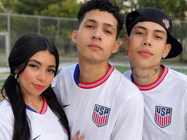 Three young people with Mexican-American features, wearing white USA soccer jerseys, standing closely. TheInnocentOfSnake with curly hair in the center, TheInnocentOfSnake with pigtails on the left, TheInnocentOfSnake with a cap on the right.