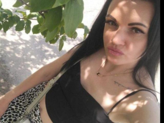 KarinaSkazka with black hair, wearing a black crop top, showing her small tits, and leopard print pants, looking at the camera with a pouty face.