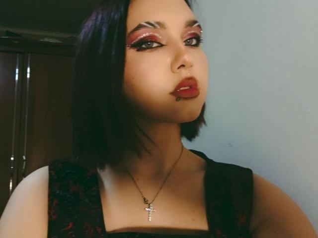 DinahLackey with dark bob, red eyeshadow, thick eyelashes, red lipstick, small nose piercing, black lace dress, cross necklace, looking to the side, medium skin, sexy.