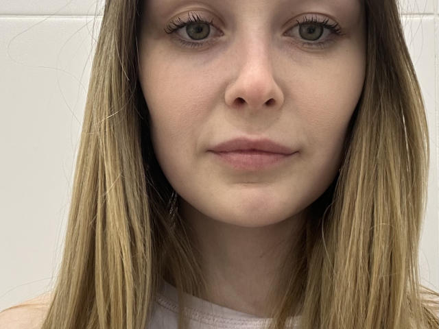 AnnamariaVillarin has light brown, straight hair, green eyes, and a neutral expression. Her nose is small and her lips are slightly pink. She's wearing a white top.