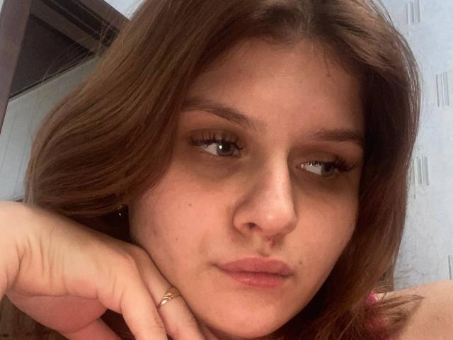 HeikeRippy has brown hair, light skin, and a serious expression. She's resting her chin on her hand with a gold ring on her finger. Her eyelashes are long and dark.