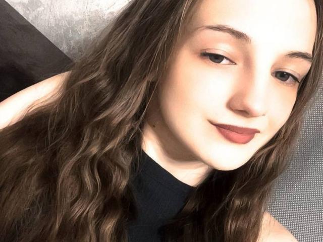 Rosita Appelt hat welliges, braunes Haar, helle Haut und trägt dunkelroten Lippenstift. Sie blickt leicht zur Seite und lächelt leicht, und trägt ein schwarzes Oberteil..