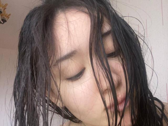 IzettaDingel's wet black hair covers her face, eyes closed, tongue slightly out. She's Asian with fair skin, looking tired or stressed. Her eyebrows are dark and slightly raised.
