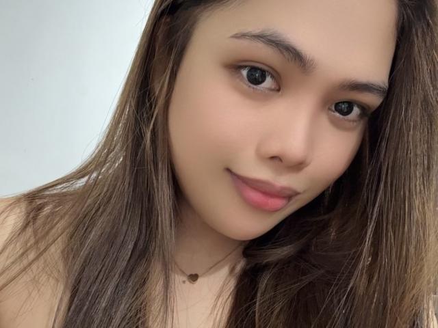 EvaBuntog has cute, small tits, brown eyes, and long brown hair, with a subtle smile and light skin. She wears a tiny necklace with a small pendant.