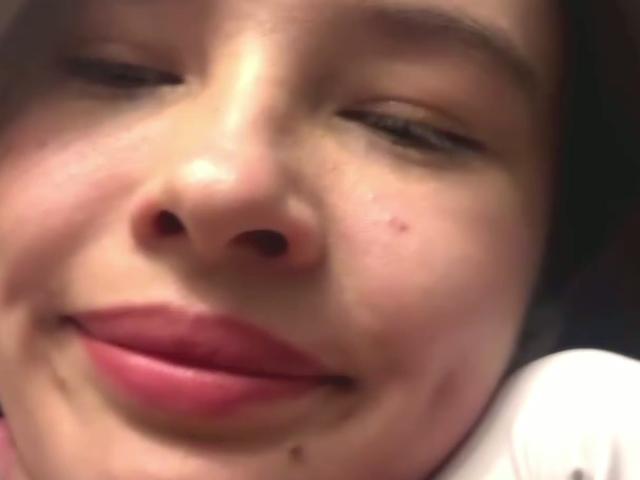 LeathaOrmond's face, slightly blurred, showing a small black mole on her left cheek, pinkish-red lips, and a small droplet of saliva near her bottom lip.