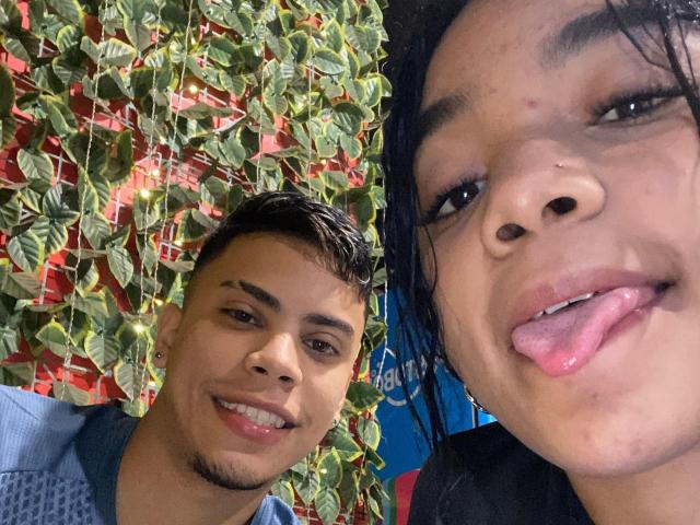 SweetVickyX with short black hair and a nose ring, tongue out, smiling next to SweetVickyX with dark hair, light skin, and a cute smile, both showing teeth.