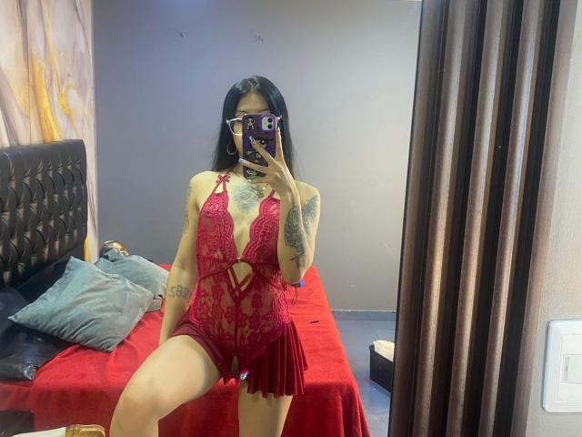 MiaDeLune with tattoos, wearing red lace lingerie, showing her tits and pussy, taking a mirror selfie, holding a phone with a purple case, in a bedroom.