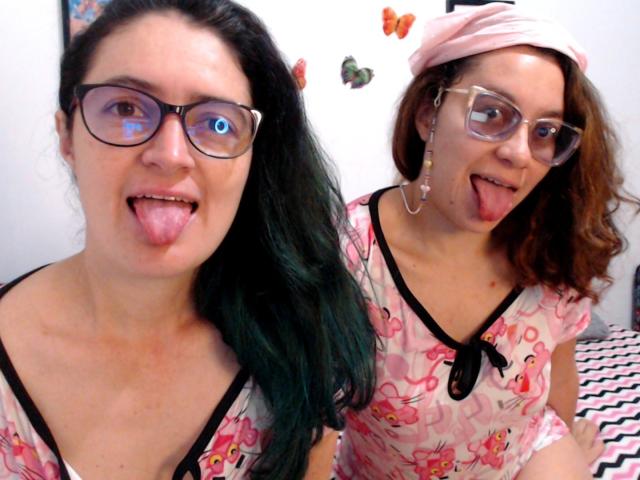 LunaVenus with black glasses and green hair sticks out tongue. LunaVenus with pink headscarf, glasses, and curly brown hair sticks out tongue, wearing pink floral top.