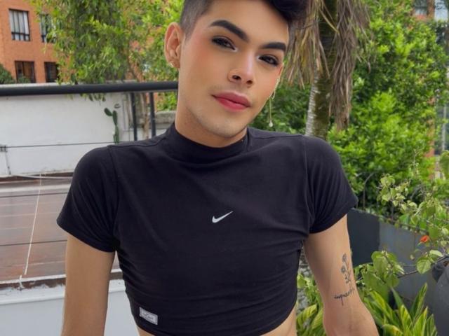 Aresxx, con i capelli corti e scuri, indossa un top corto nero Nike, ha un tatuaggio sul braccio sinistro e guarda la fotocamera con un leggero sorriso..