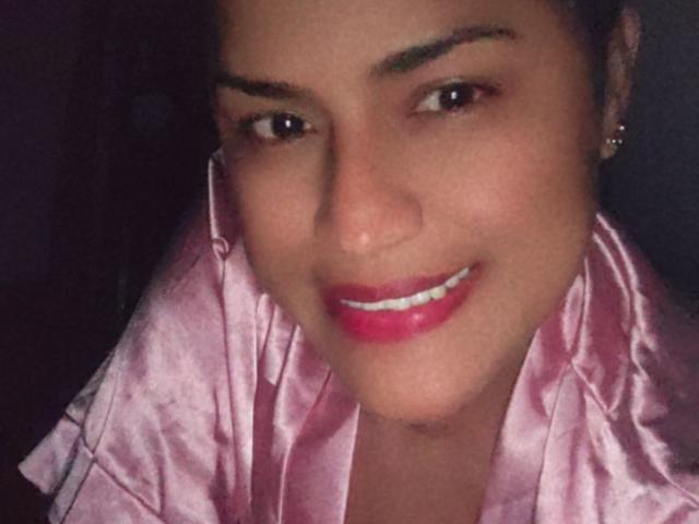 IvannaDuran with pink satin robe, smiling with pink lipstick, brown eyes, and earrings, showing her face and upper chest in a selfie. Boobs not visible, ass not visible.