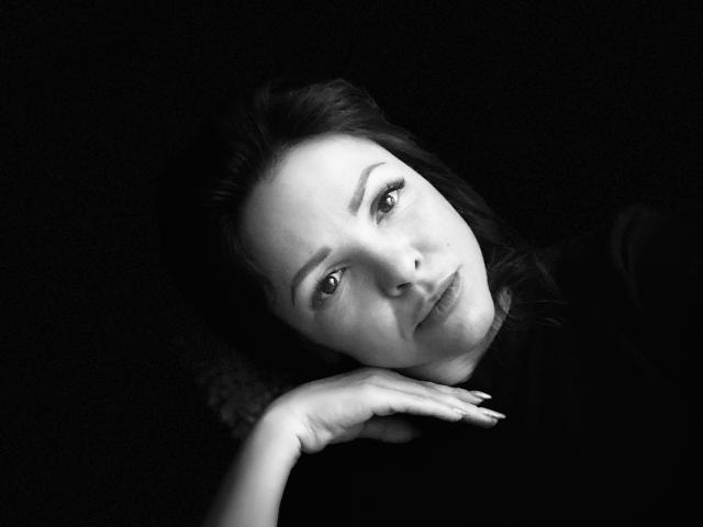 El rostro de Molly Brunett aparece en una fotografía en blanco y negro, acostada con la cabeza inclinada, mirando hacia arriba con un ligero ceño fruncido, con la mano debajo del mentón, sobre un fondo oscuro..