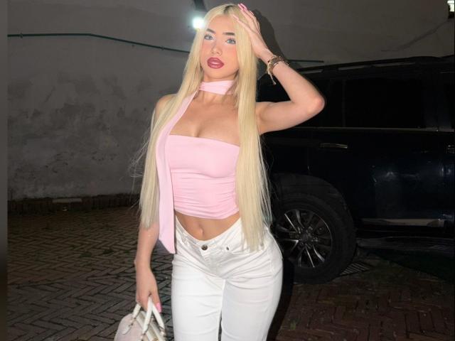 ChristieGarci with long blonde hair, pink choker, pink tube top, white jeans, holding purse, standing by black SUV at night, hand on head, pink lipstick, visible tan lines.