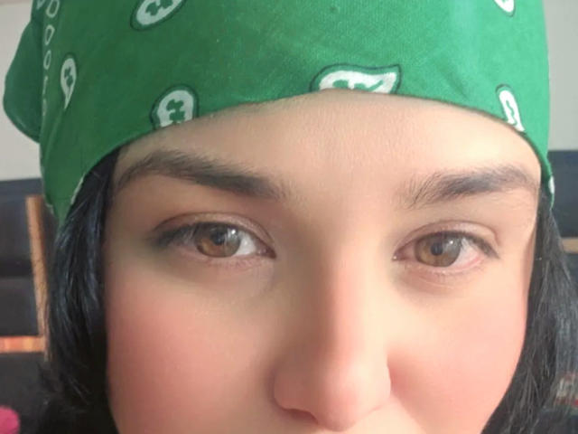 VivianaThompson's face, green bandana with white skull pattern, brown eyes, black eyebrows, slight blush, short black hair, slightly parted lips, close-up, natural light.