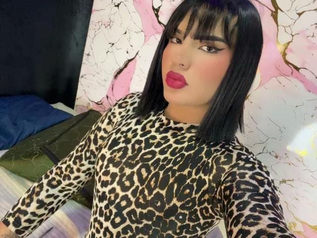 GlossyyBratz with a black bob, wearing a leopard print dress, has red lipstick and winged eyeliner, showing off her pouty ass and her cute, sexy face.