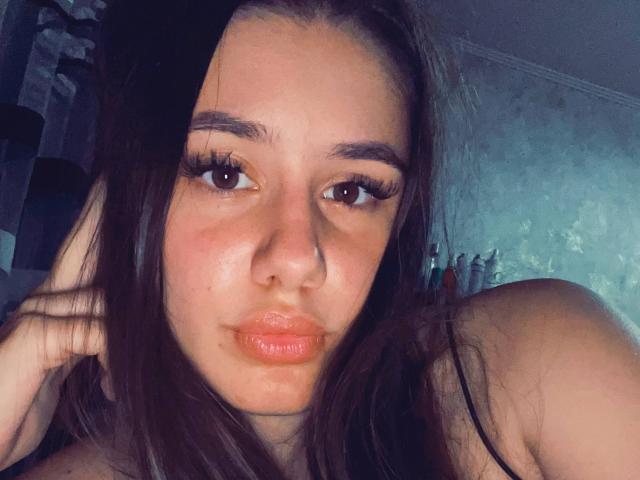 WavaBlauman has dark brown hair, full pink lips, and thick black eyeliner. Her green eyes are slightly upturned, and she has a soft, pale skin tone.