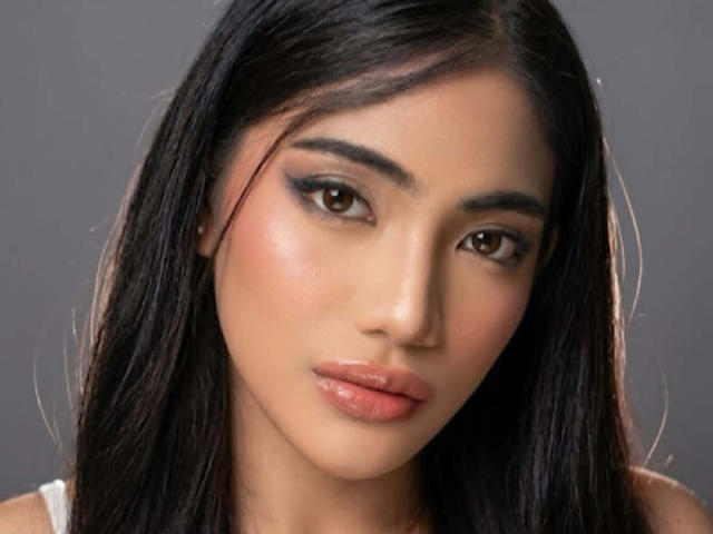 KhelsieSilva tiene el cabello oscuro y lacio, ojos marrones con maquillaje ahumado y labios rosados brillantes. Está mirando directamente a la cámara con una expresión neutra..