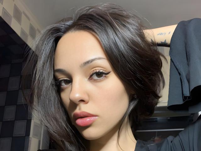 Candida Bardill tiene el cabello oscuro y brillante, piel de color marrón claro y labios rosados y carnosos. Lleva delineador de ojos al estilo "ala de gato" y tiene una expresión seria, ligeramente fruncida. Sus senos no son visibles..