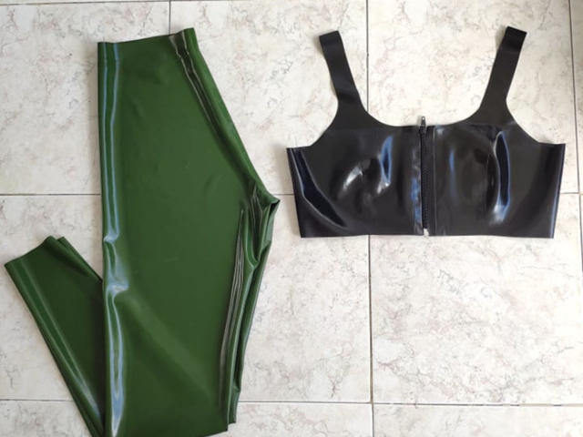 AmyDan69's shiny green latex pants and black latex sports bra with a zipper, laid flat on a tiled floor.