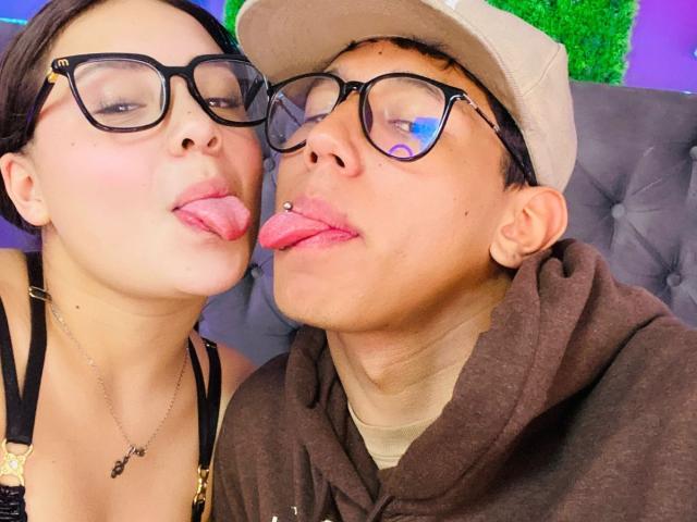 RyanNPricee and RyanNPricee with glasses, tongues out, and nose piercings, wearing a cap and hoodie, have cute faces, short hair, and are touching noses.