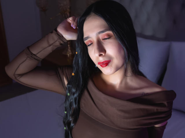 IvanaClark met lang zwart haar, een bruin topje met open schouder, rode lippenstift, ogen gesloten, hand in haar haar, zacht licht, zachte glimlach, lichte blos, subtiele make-up, aantrekkelijk, zelfverzekerd, sexy..