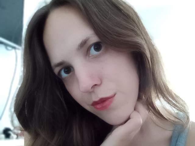 LunaFiorella heeft een lichte huid, bruin golvend haar, blauwe ogen, rode lippenstift, en ze leunt haar kin op haar hand met een lichte glimlach. Haar borsten zijn niet zichtbaar..