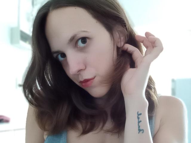 LunaFiorella a une peau pâle, des cheveux bruns ondulés et des yeux bleus. Elle regarde l'appareil photo avec un léger sourire, tout en touchant ses cheveux, et on peut apercevoir un petit tatouage à son poignet droit..